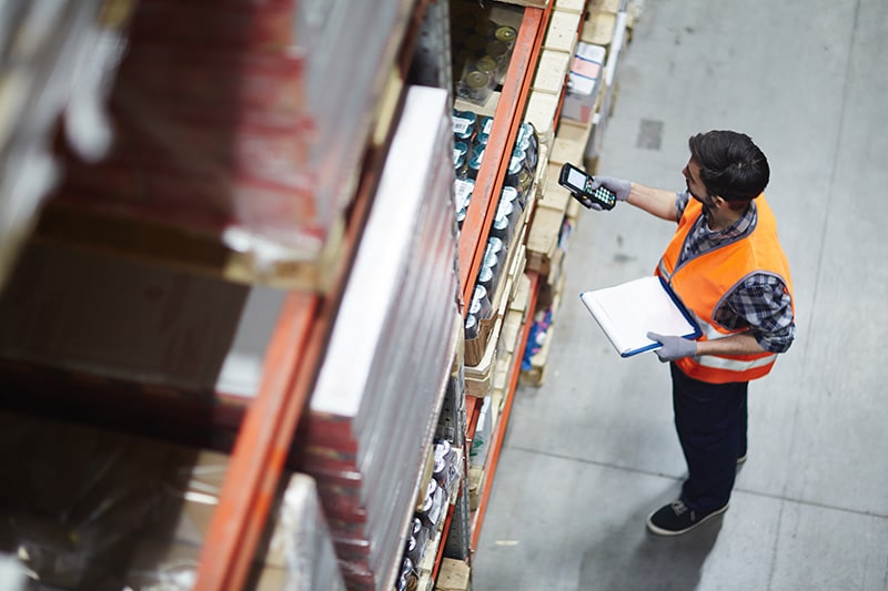 warehouse employee scanning boxes of inventory to distribute