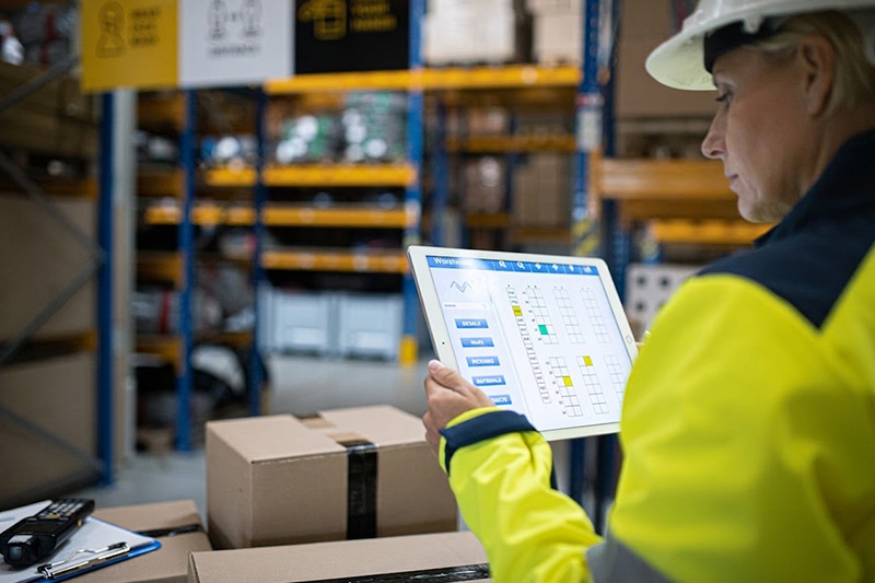 woman in warehouse looking at her tms on a tablet